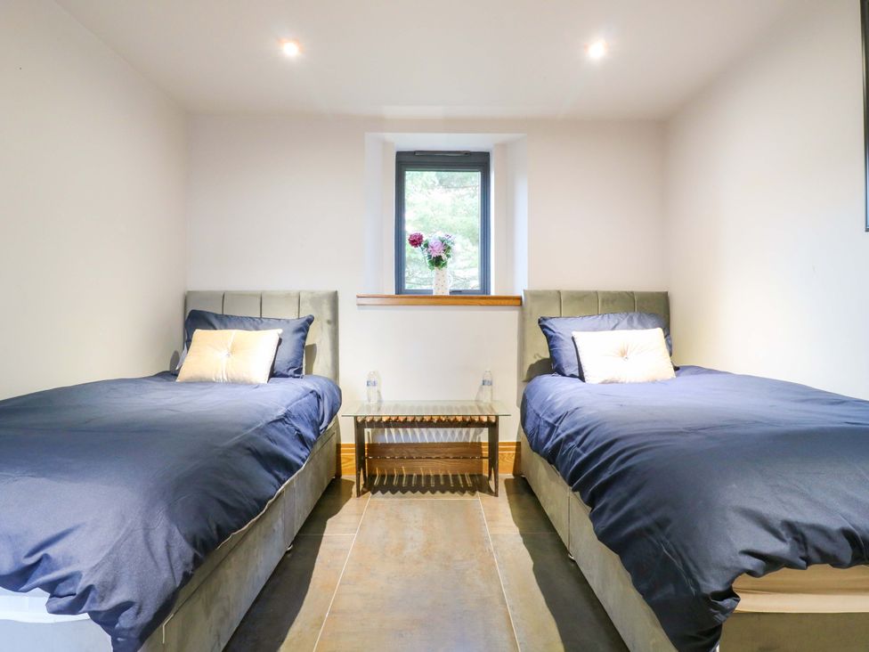 A bedroom with two beds and a table at The Lodge @ Lodge Farm Bedford