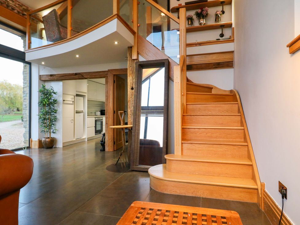 A living room with a staircase and kitchen visible at The Lodge @ Lodge Farm Bedford
