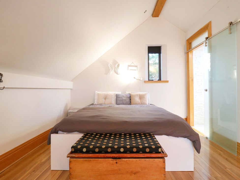A bedroom with a bed, bench and window at The Lodge @ Lodge Farm Bedford