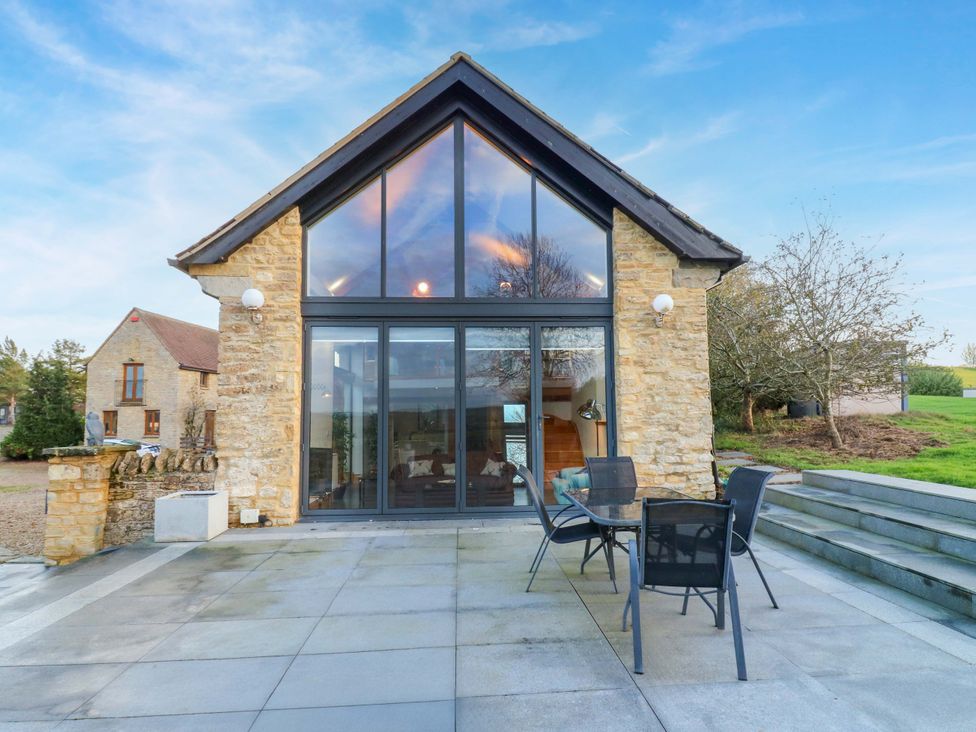 An outdoor area with a stone building and patio furniture at The Lodge @ Lodge Farm Bedford