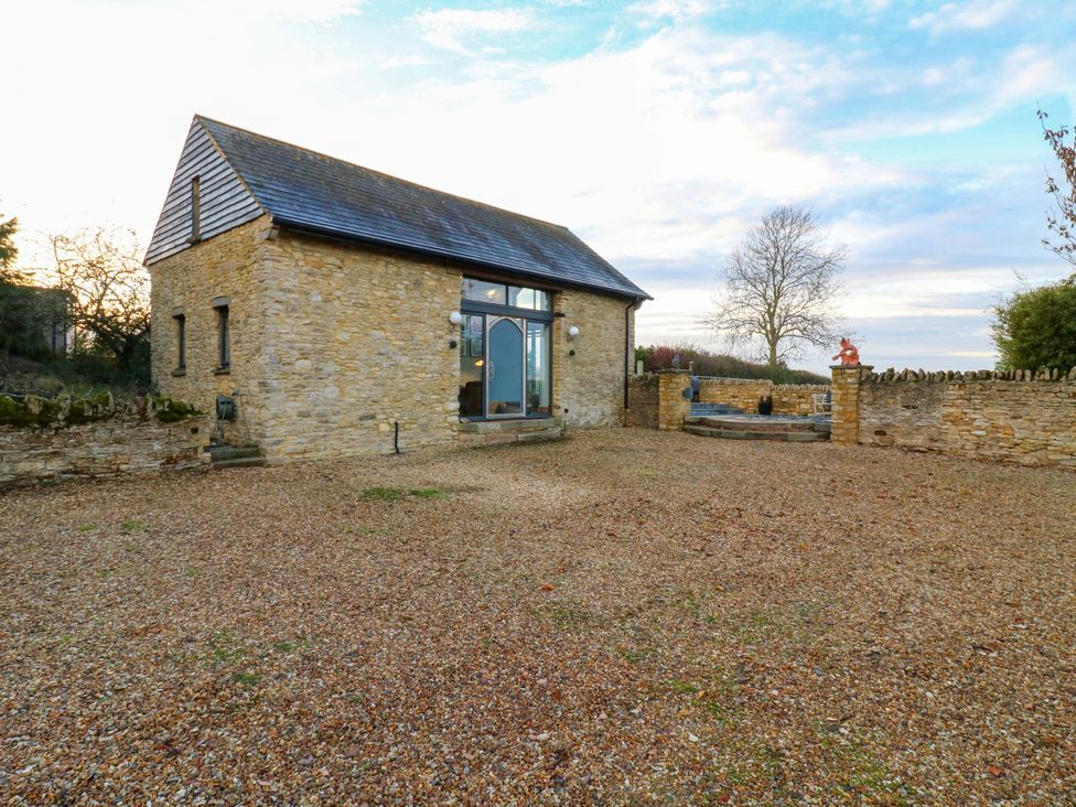 A building with windows and a door surrounded by gravel and a stone wall at The Lodge @ Lodge Farm in Bedford