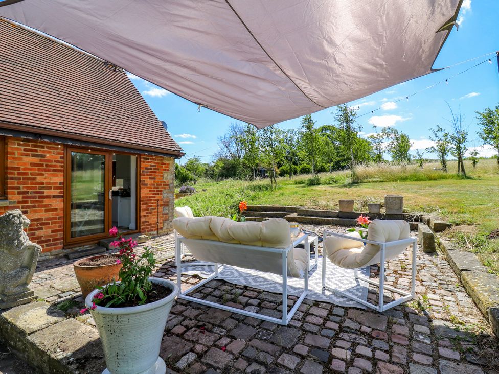 An outdoor seating area with a sofa and table at Barn Owl Cottage in Carlton near Harrold
