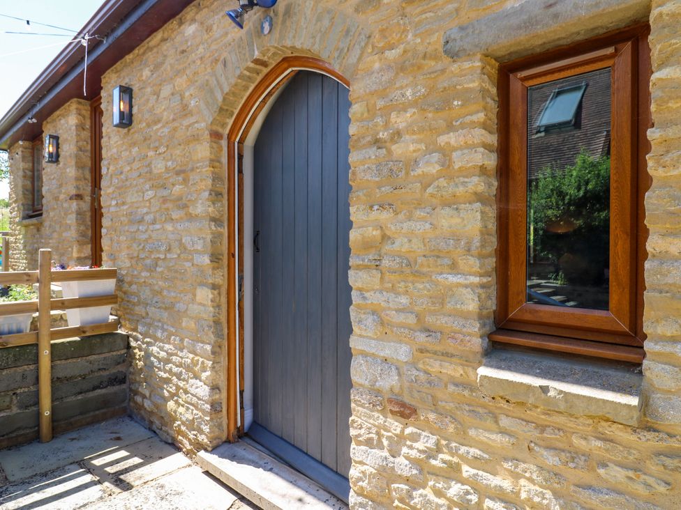 An entrance with a stone wall and a wooden door at Barn Owl Cottage Carlton near Harrold