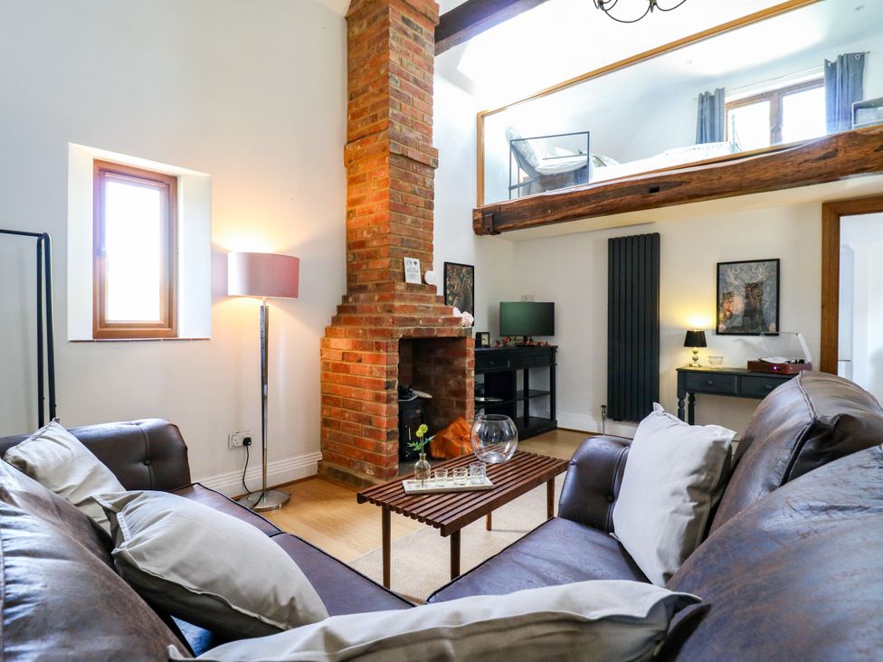 A living room with a sofa and fireplace at Barn Owl Cottage in Carlton near Harrold