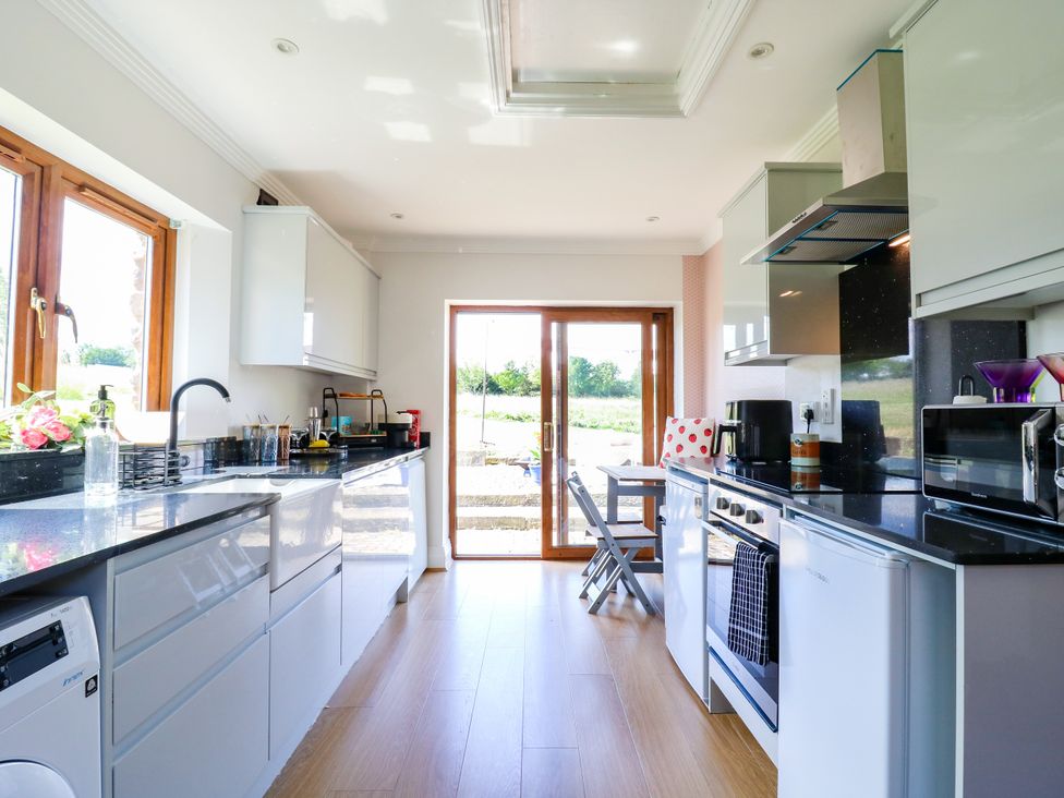 A kitchen with appliances and an outdoor view at Barn Owl Cottage Carlton near Harrold