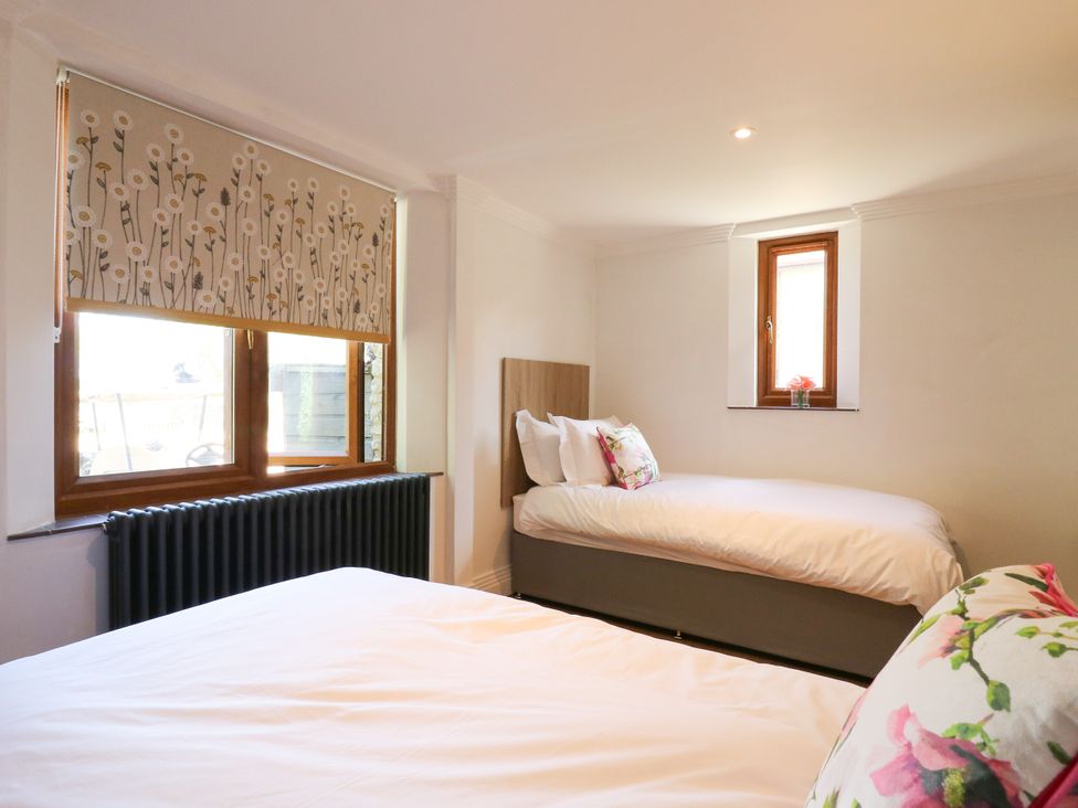 A bedroom with two beds and a window at Barn Owl Cottage in Carlton near Harrold