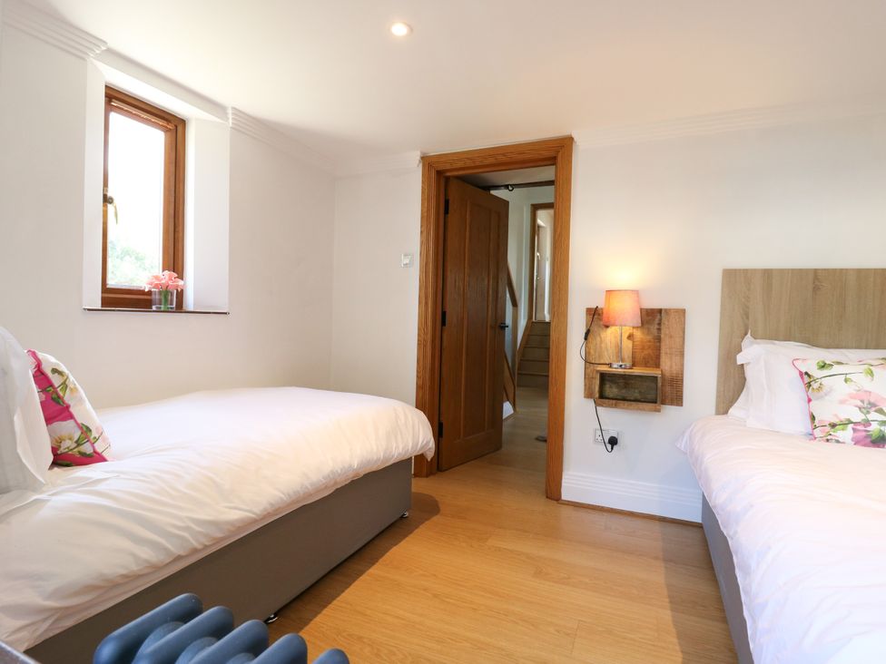 A bedroom with two beds and a window at Barn Owl Cottage in Carlton near Harrold