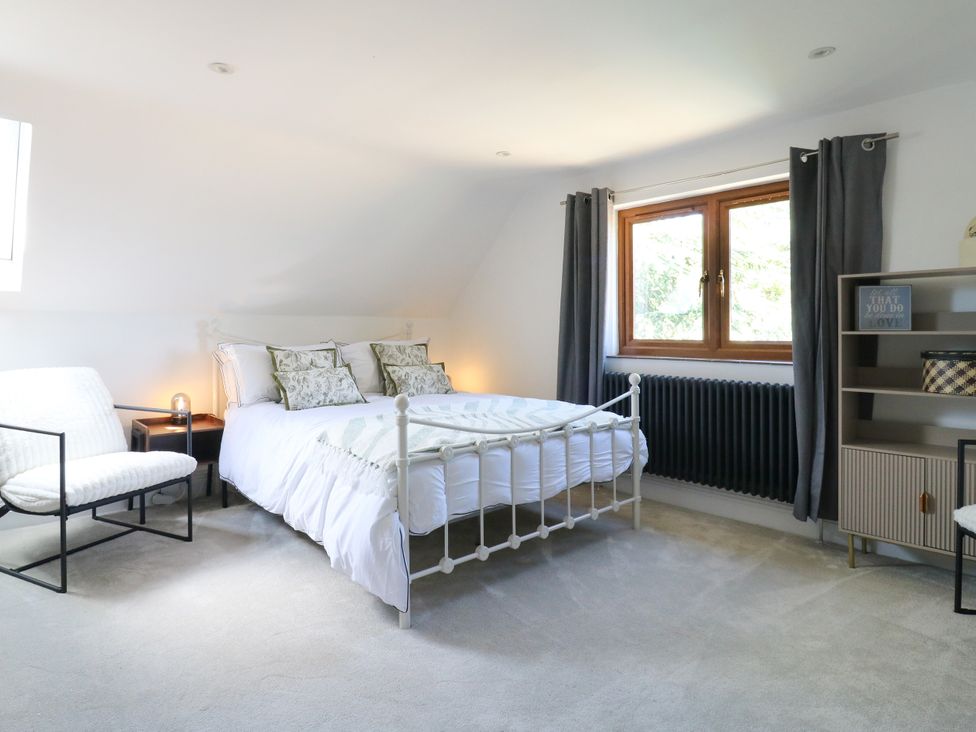 A bedroom with a bed and armchair at Barn Owl Cottage in Carlton near Harrold