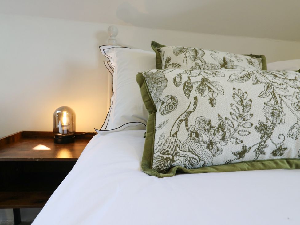 A bed with pillows and a lamp on a nightstand at Barn Owl Cottage Carlton near Harrold