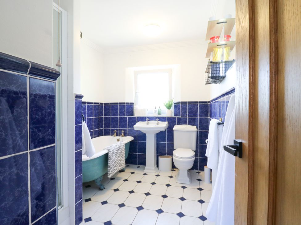 A bathroom with a bathtub, toilet, and sink at Barn Owl Cottage Carlton near Harrold