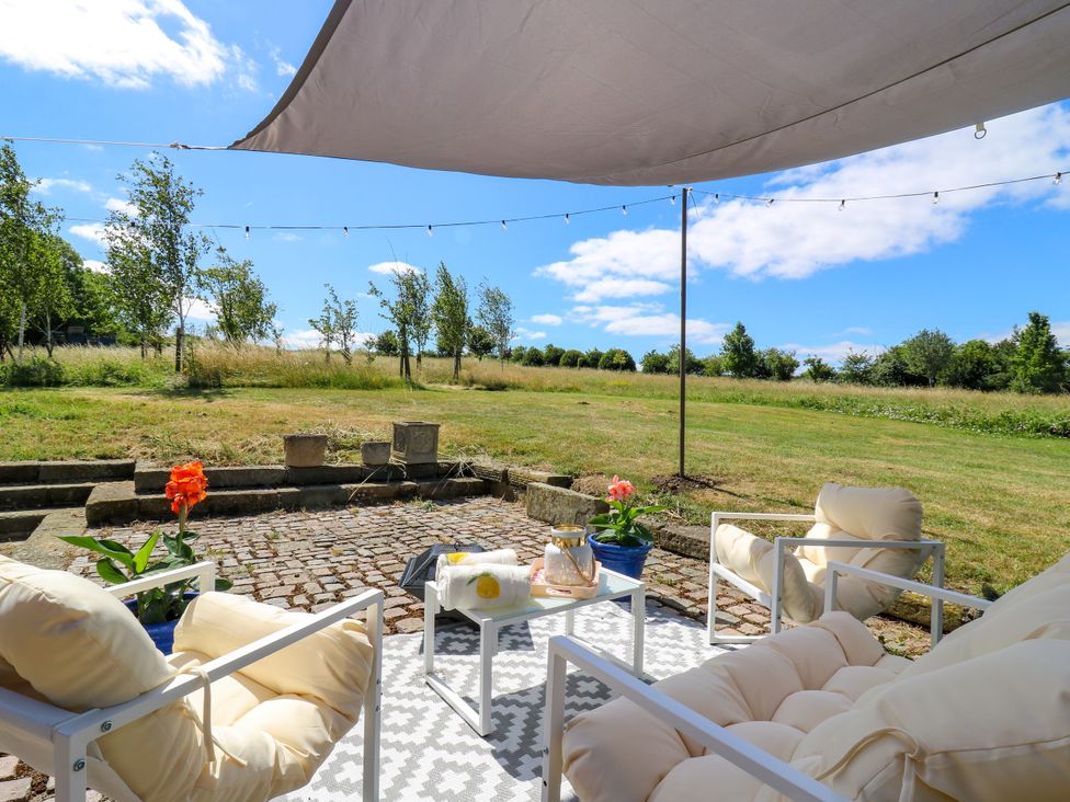 Outdoor patio with seating and flower pots at Barn Owl Cottage Carlton near Harrold