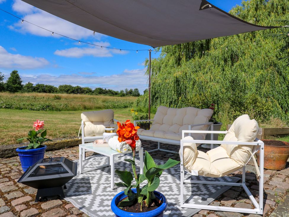 An outdoor seating area with a sofa table and plants at Barn Owl Cottage Carlton near Harrold