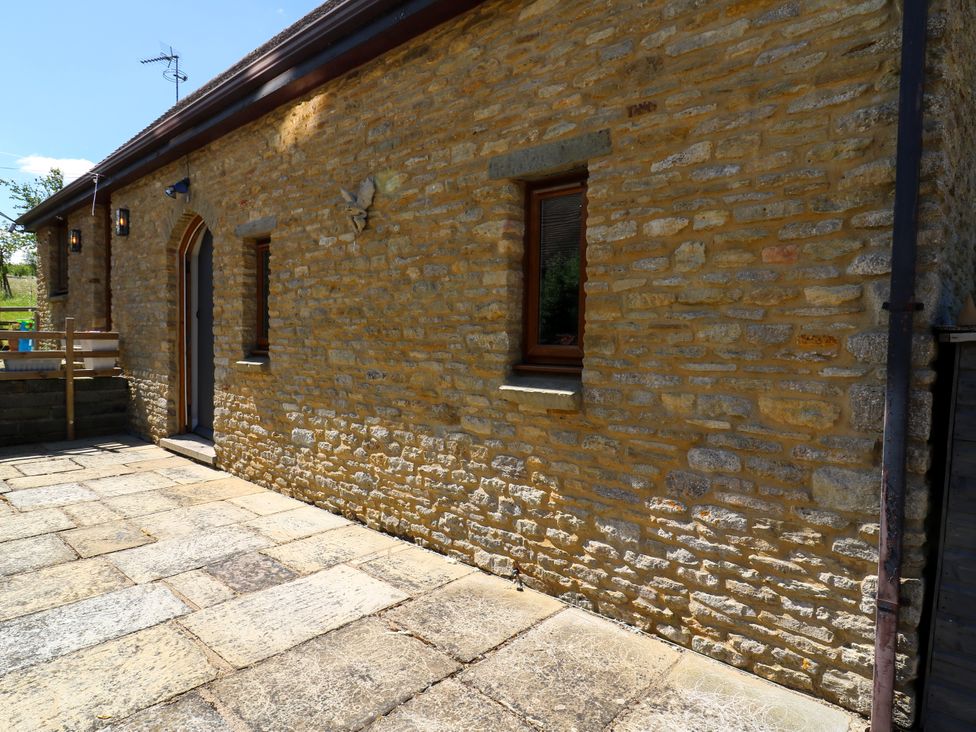 An outdoor area with a stone wall and patio at Barn Owl Cottage Carlton near Harrold