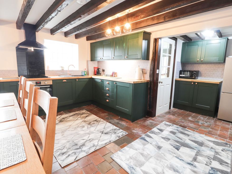 A kitchen with cabinets, sink, and refrigerator at Cae Adar Farm in Wrexham