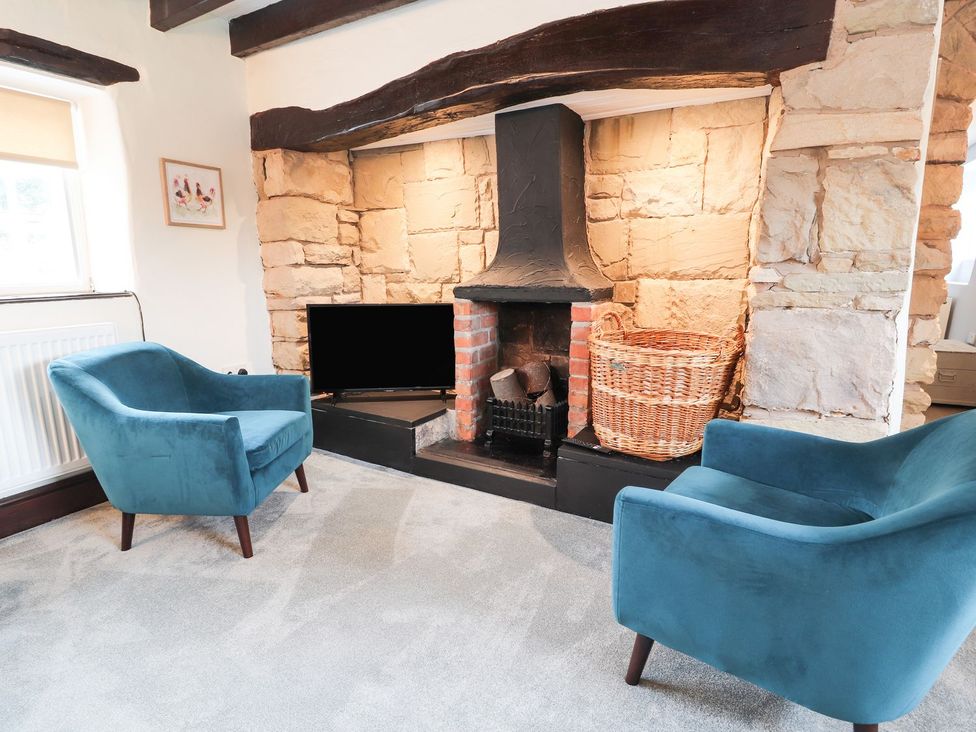 A living room with a fireplace and armchairs at Cae Adar Farm in Wrexham