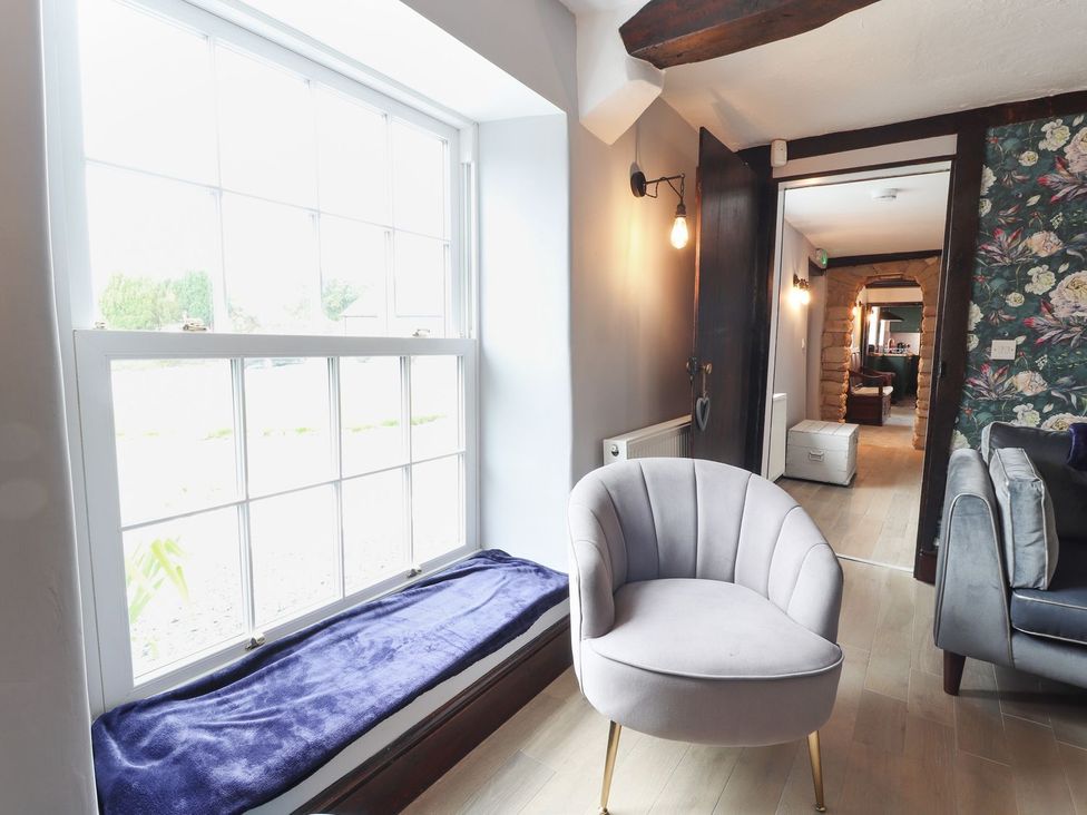 A snug with a chair by a window at Cae Adar Farm in Wrexham