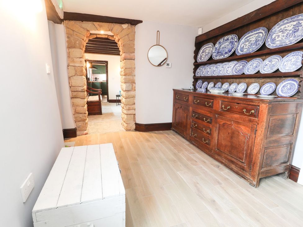 A dining area with a kitchen unit holding plates and a wooden box at Cae Adar Farm Wrexham