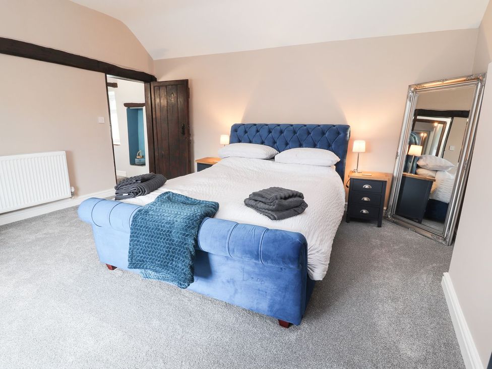 A bedroom with a blue bed and nightstand at Cae Adar Farm Wrexham
