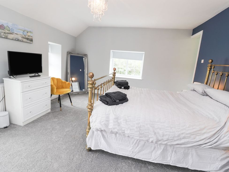 A bedroom with a bed, television, and dressing table at Cae Adar Farm in Wrexham
