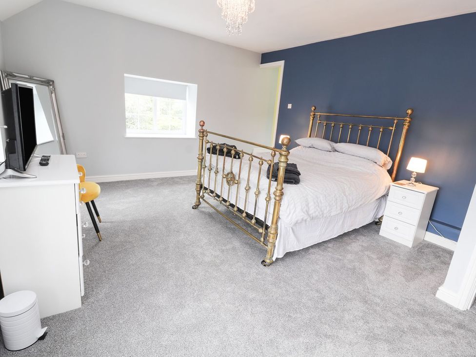 A bedroom with a metal bed and television at Cae Adar Farm in Wrexham