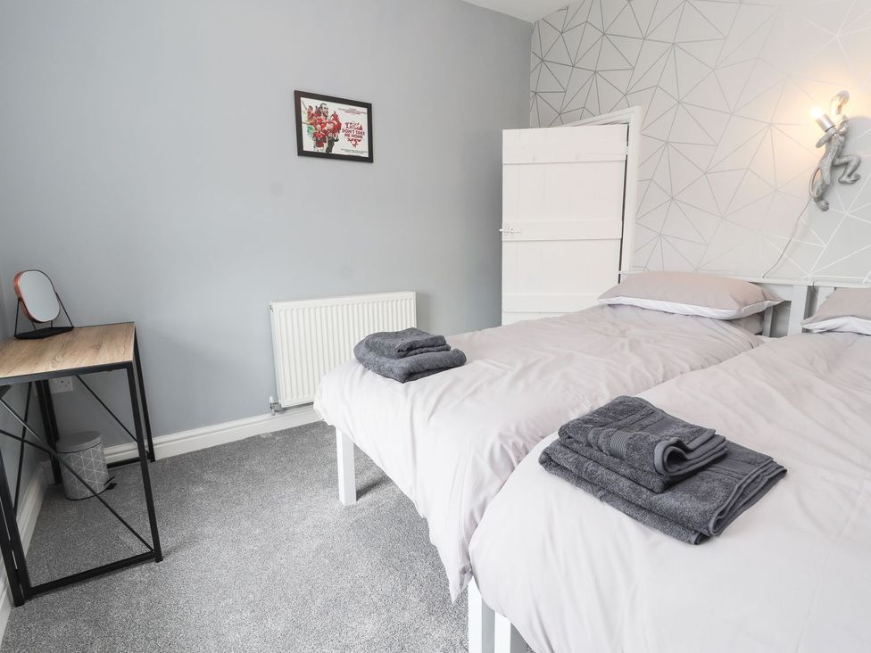 A bedroom with two beds and a desk at Cae Adar Farm Wrexham