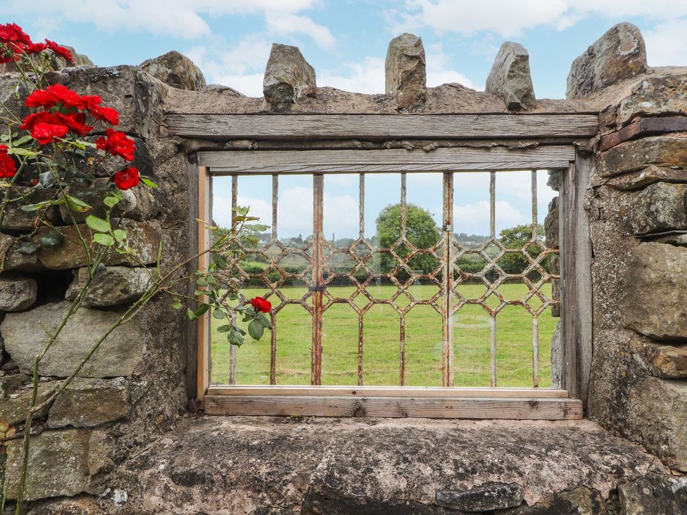 A view through a wooden frame in a stone wall with roses at Cae Adar Farm Wrexham