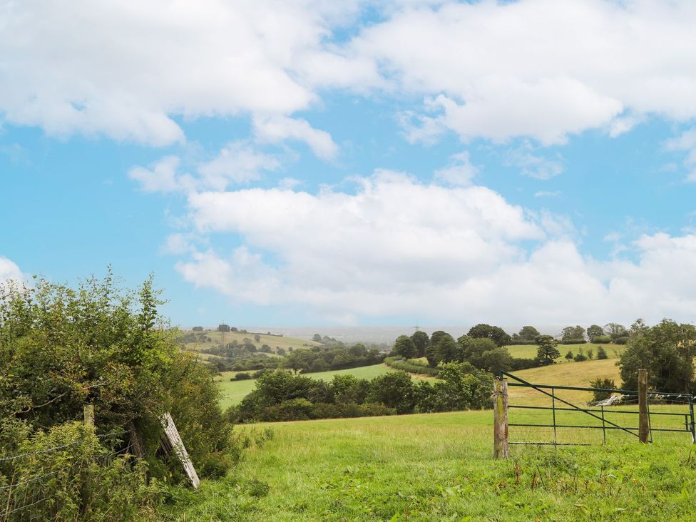 A landscape view with a gate and trees at Cae Adar Farm in Wrexham