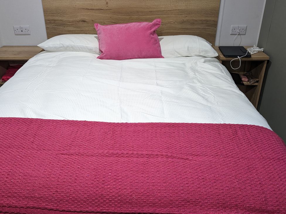 A bed with a pink throw and pillow at Willerby Ellerrton (delyn) Prestatyn