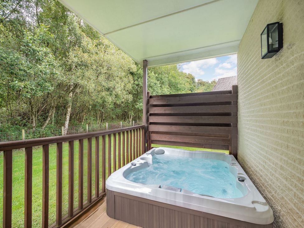 A hot tub on a deck in an outdoor area at Arran Lodge Spa Dailly