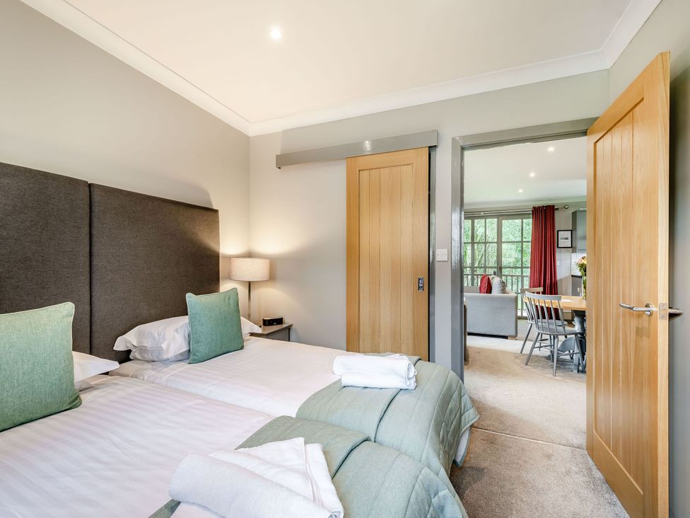 A bedroom with twin beds and an open doorway at Arran Lodge Spa Dailly