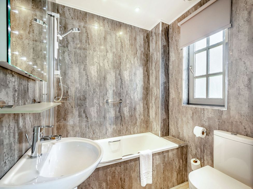 A bathroom with a bathtub, sink, and toilet at Arran Lodge Spa in Dailly