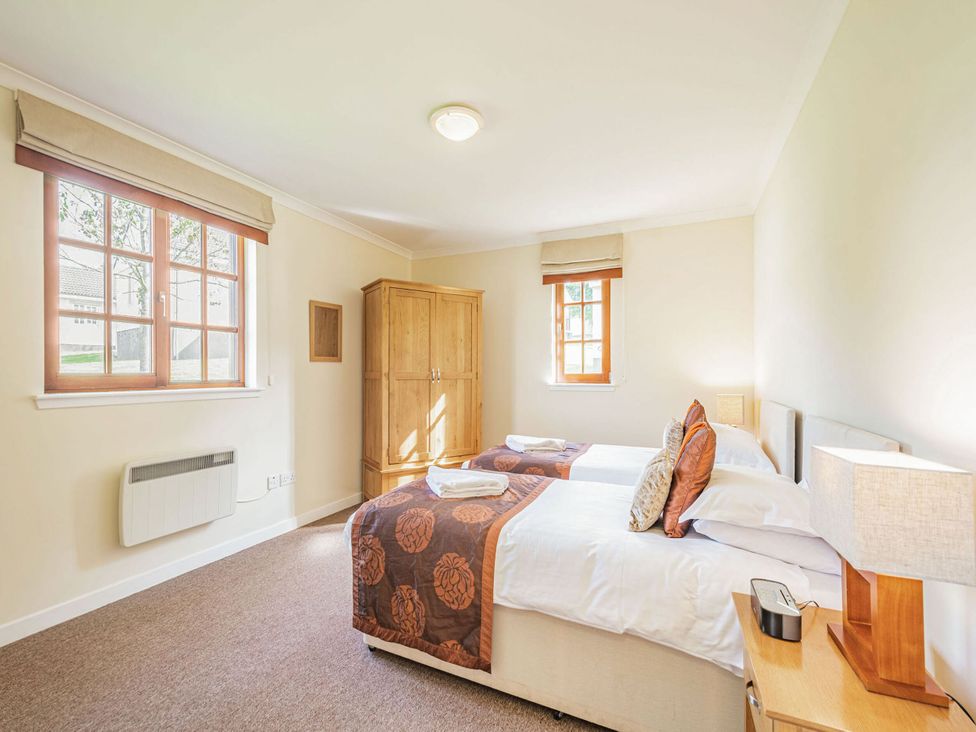 A bedroom with two beds and wooden wardrobe at Turnberry in Dailly