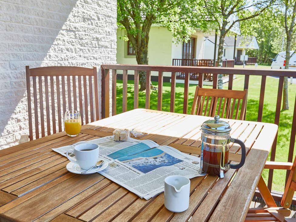 An outdoor dining area with a coffee cup and newspaper at Brunston (Pet) Dailly