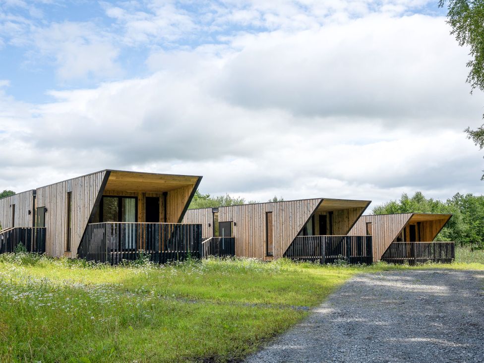 Wooden lodges with balconies in a grassy area at Orka Duo 2.0 (Pet) Dumfries