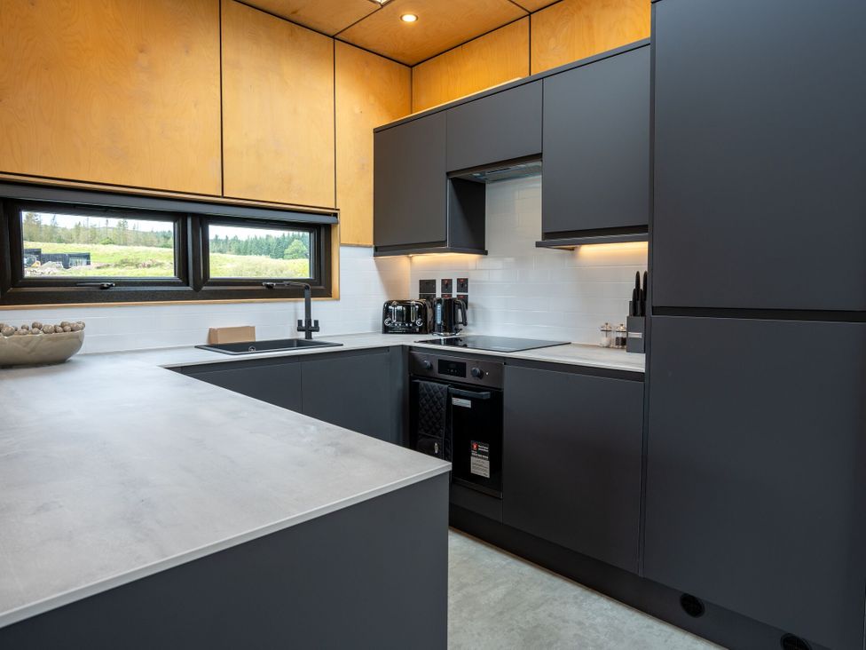 A kitchen with dark cabinets and a window at Orka Duo 2.0 (Pet) Dumfries