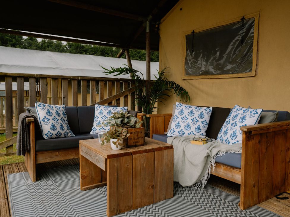 A seating area with wood furniture and decorative cushions at Standard Safari Tent in Fair Oak