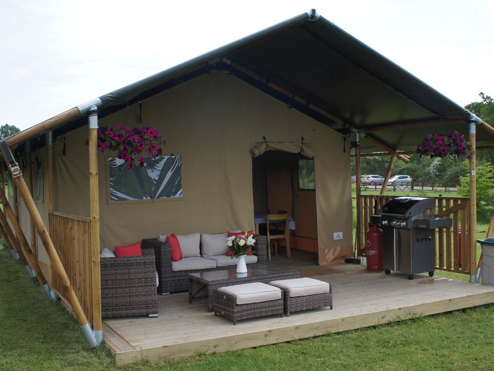 An outdoor seating area with a tent, sofa, table, and barbecue grill at Standard Safari Tent in Fair Oak