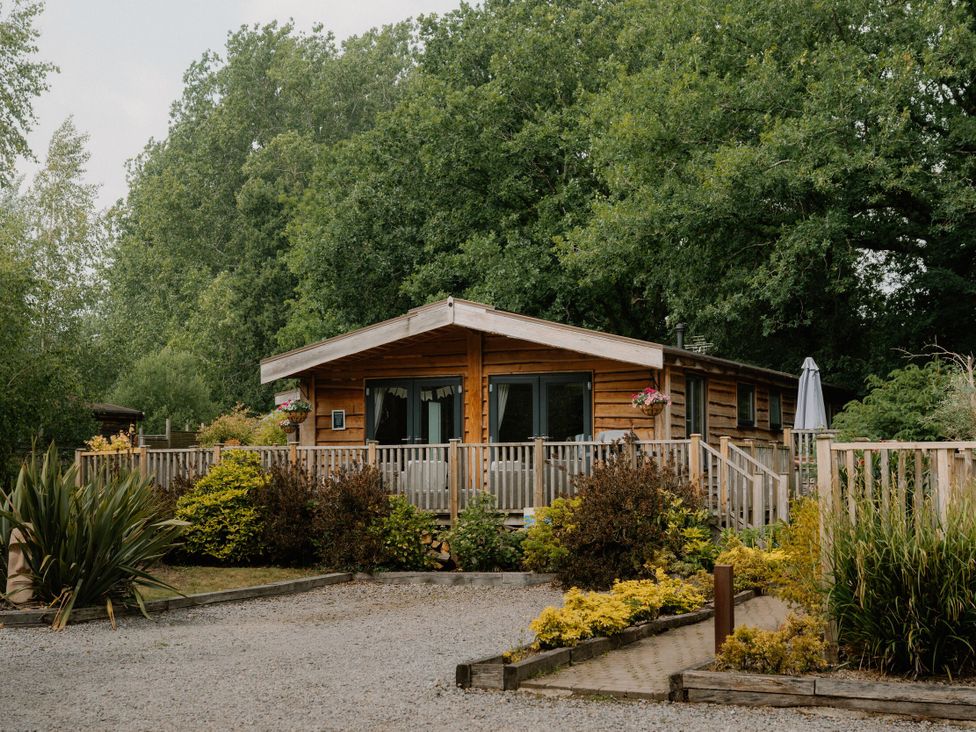 An outdoor view of a wooden lodge surrounded by greenery at Spitfire Lodge in Fair Oak