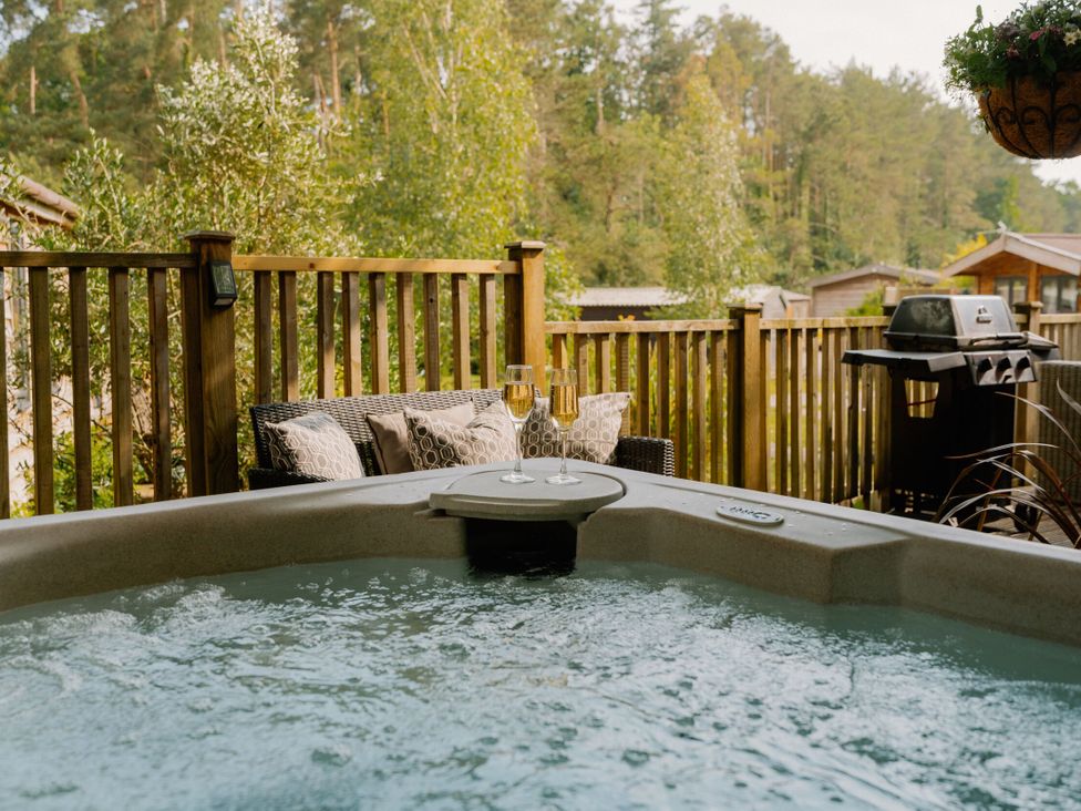 A hot tub with outdoor furniture and barbecue at Spitfire Lodge in Fair Oak