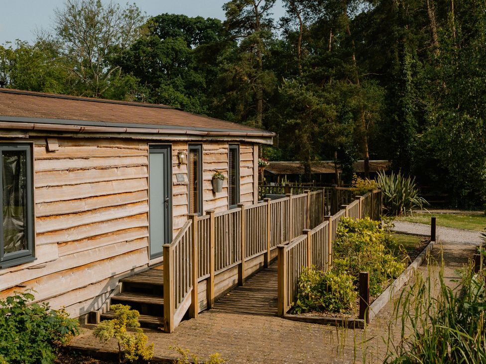 A cabin with a wooden deck and pathway at Spitfire Lodge in Fair Oak