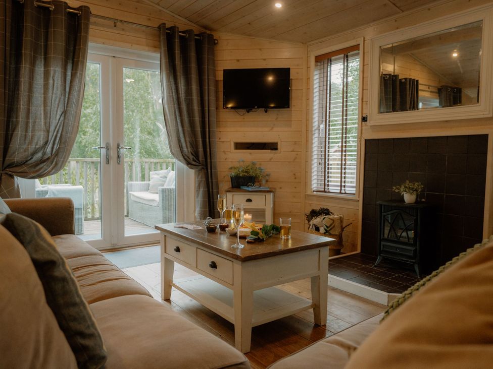A living room with a coffee table and television at Spitfire Lodge in Fair Oak