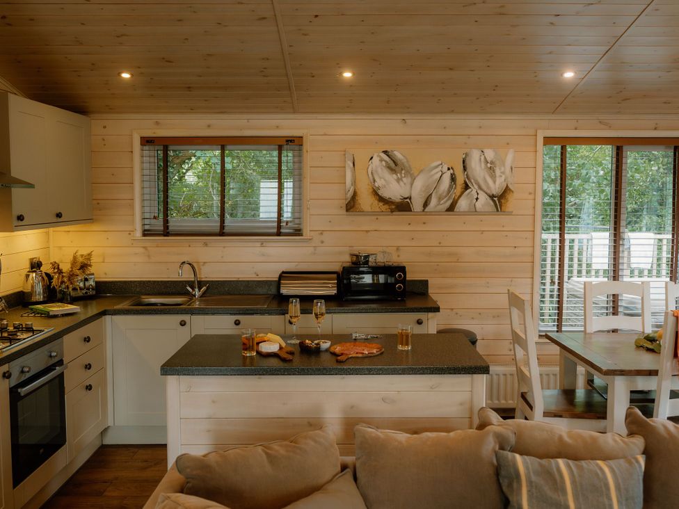 A kitchen with cabinets and a dining table at Spitfire Lodge in Fair Oak