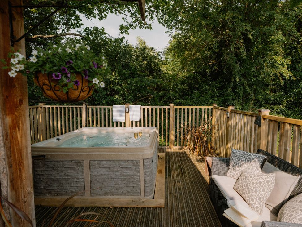 An outdoor living area with a hot tub and seating at Spitfire Lodge in Fair Oak