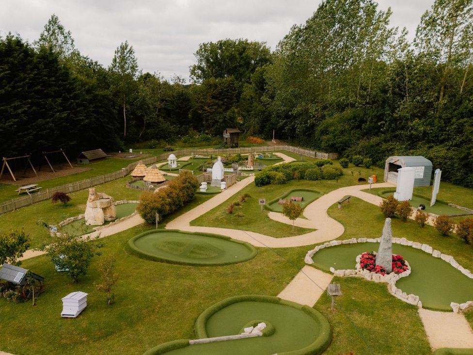 An outdoor mini golf course with trees and benches at Spitfire Lodge in Fair Oak