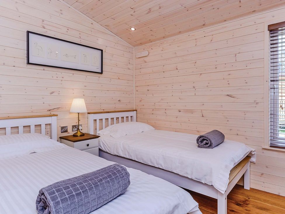 A bedroom with two beds and a bedside lamp at Lancaster Lodge in Fair Oak