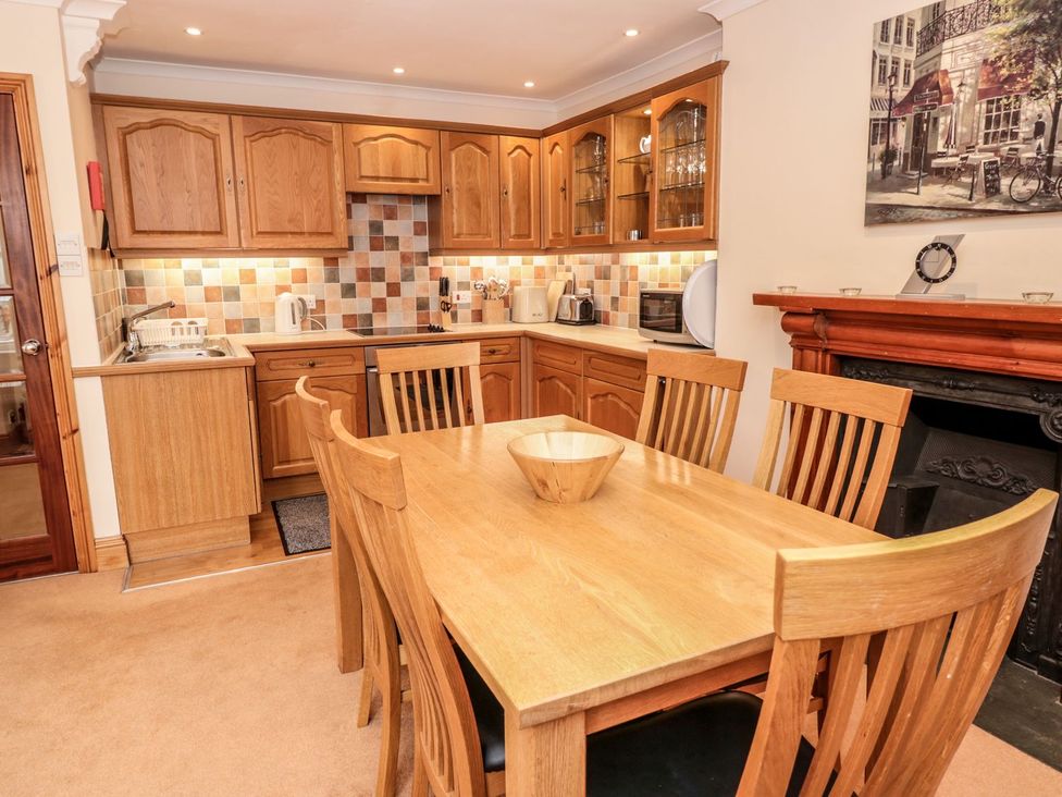 A kitchen with wooden cabinets and a dining table at The Little Clock House in Dartmouth
