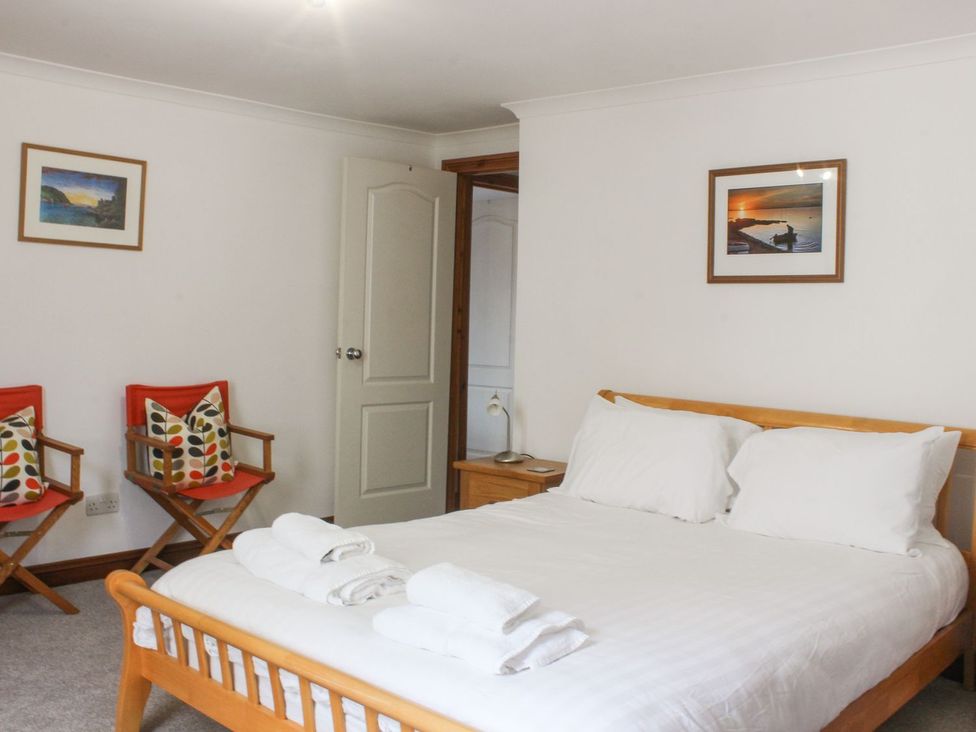 A bedroom with a bed and two chairs at The Little Clock House in Dartmouth