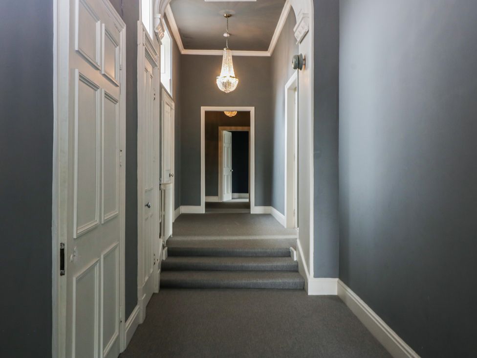 A hallway with doors and a chandelier at Frenchay Park House in Bristol