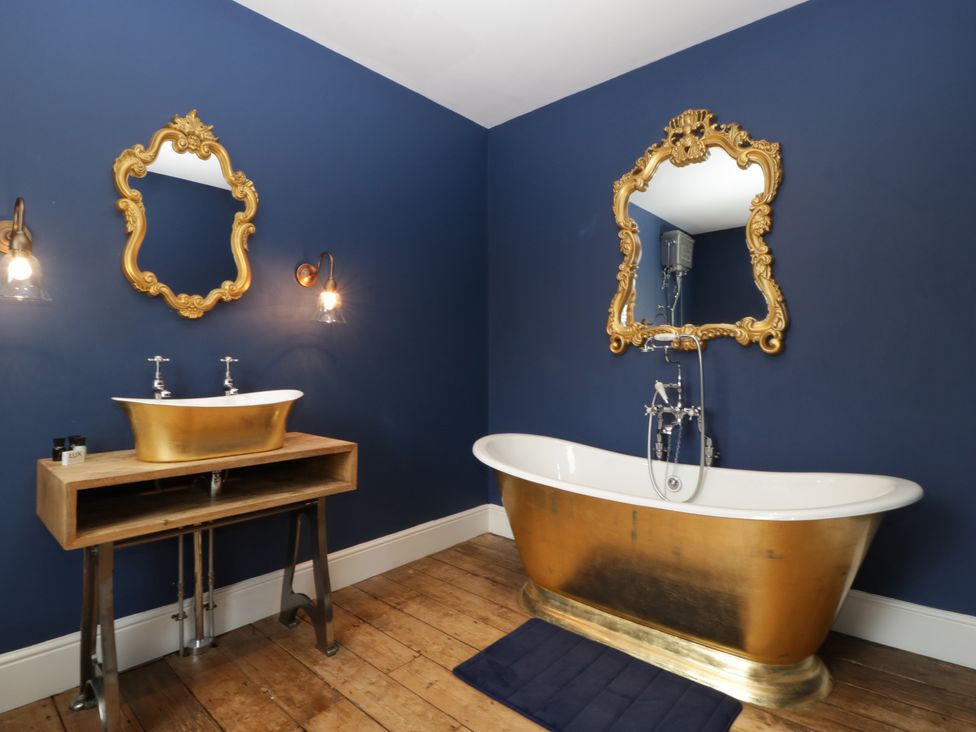 A bathroom with a golden bathtub and sink at Frenchay Park House in Bristol