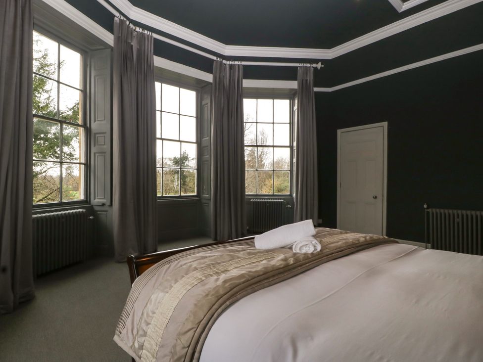 A bedroom with a bed and windows at Frenchay Park House in Bristol